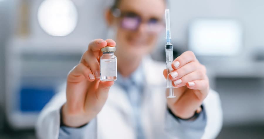 Pharmacist holding a vaccine vial and syringe